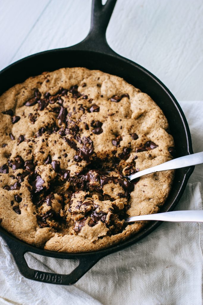 chocolate chip cookie skillet in a cast iron pan with two spoons