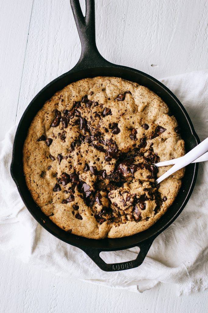 chocolate chip cookie skillet in a cast iron pan with two spoons