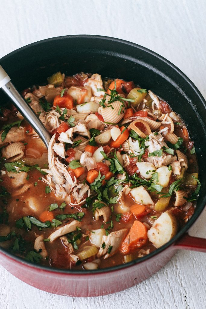 chicken noodle soup in red pot with spoon