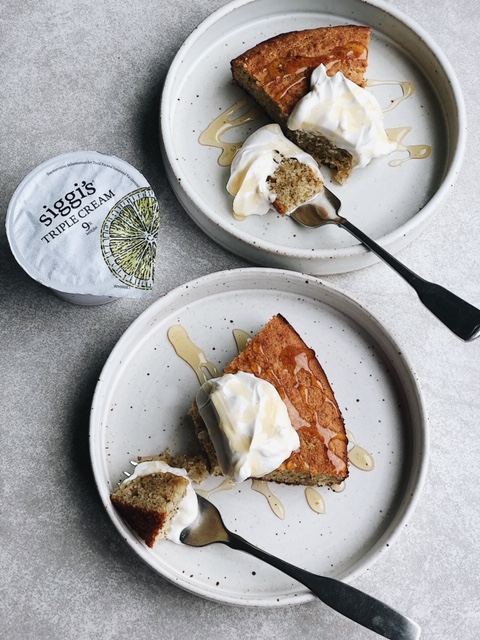 2 slices of cake with dollop of yogurt and drizzle of honey on white plates