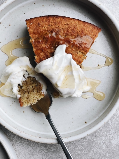 slice of cake with dollop of yogurt and drizzle of honey on white plate