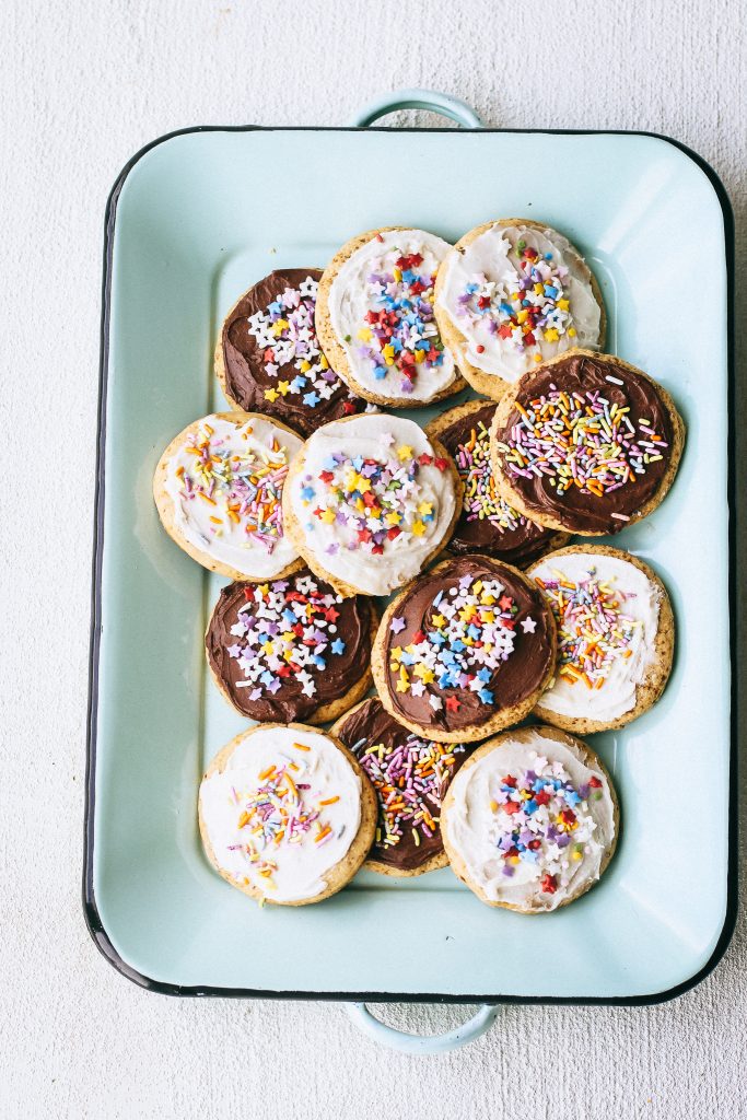 sugar cookies with frosting and sprinkles on a blue tray