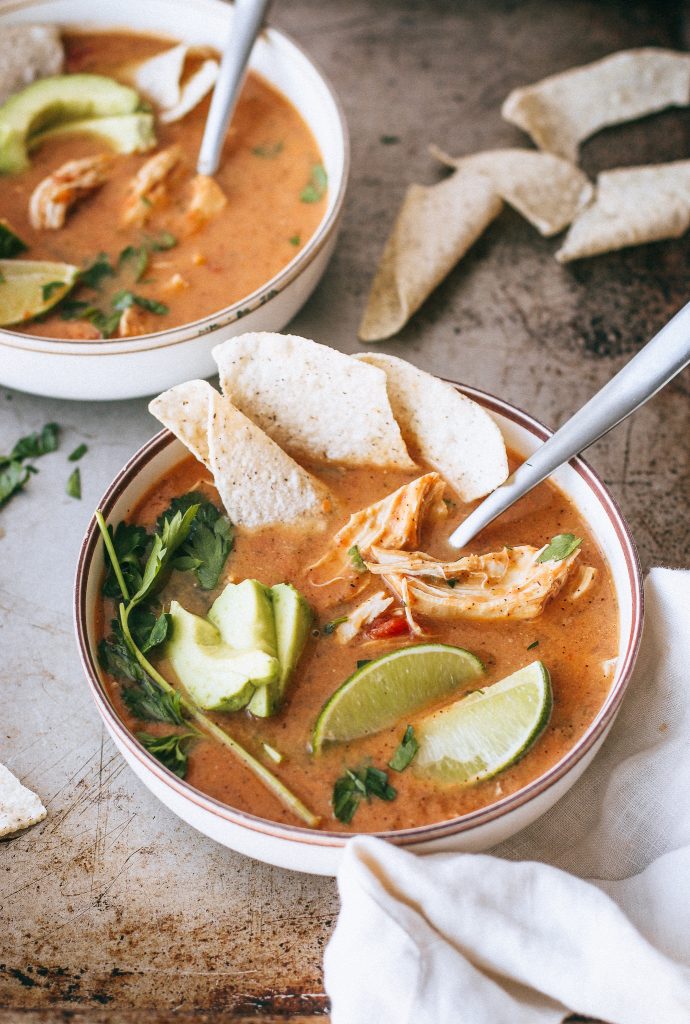 chicken tortilla soup with tortilla chips in a white bowl