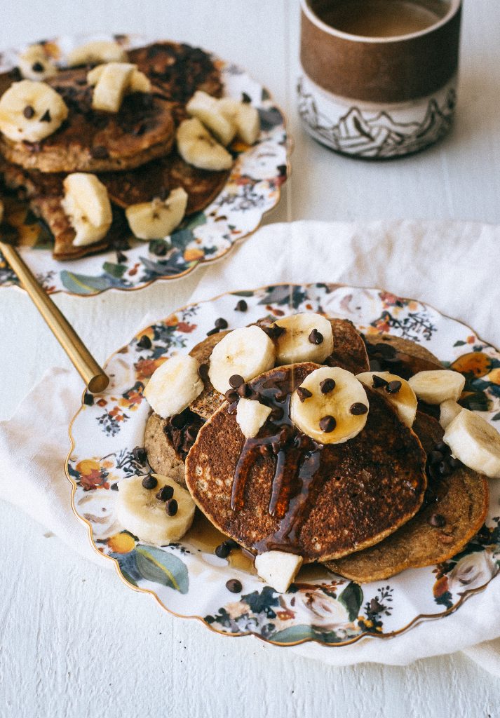 pancakes with bananas and syrup on floral plates and coffee cup
