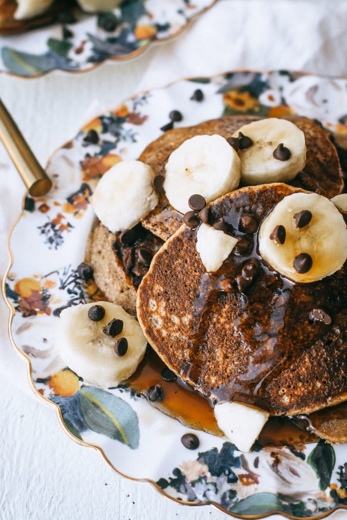 pancakes with bananas and syrup on floral plate