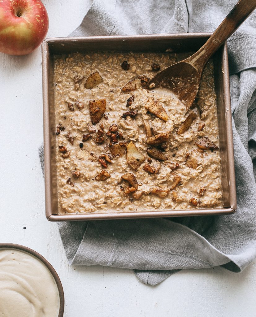 unbaked apple oatmeal mixture in baking dish with wooden spoon