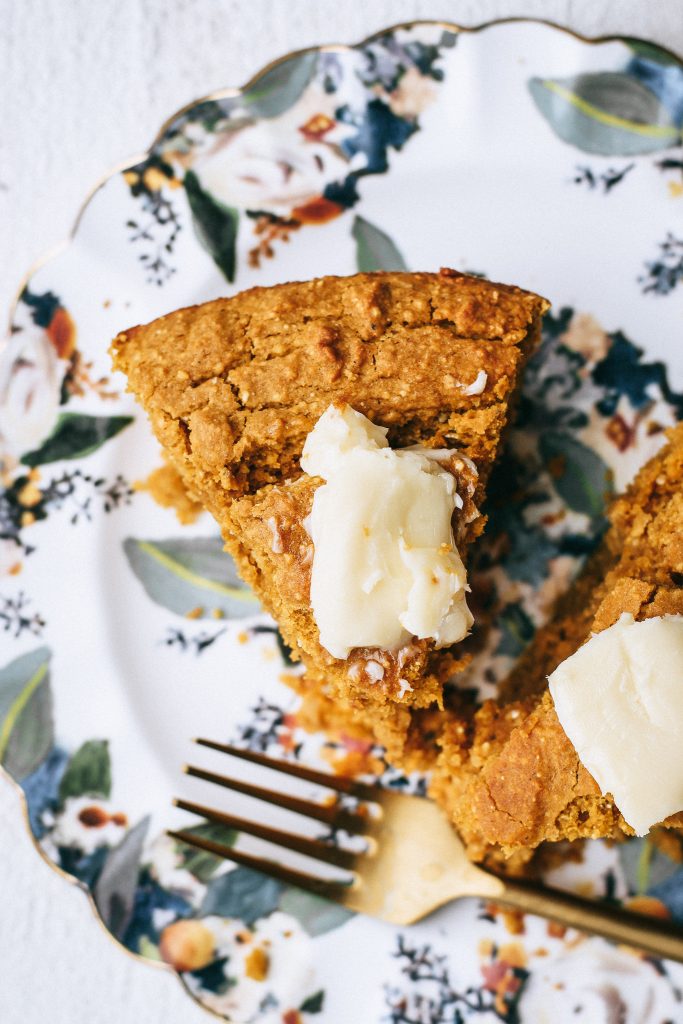 slice of cornbread with pat of butter on floral plate