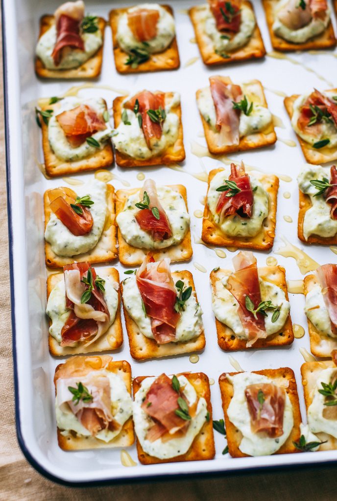 prosciutto and ricotta on crackers with honey drizzle on white tray