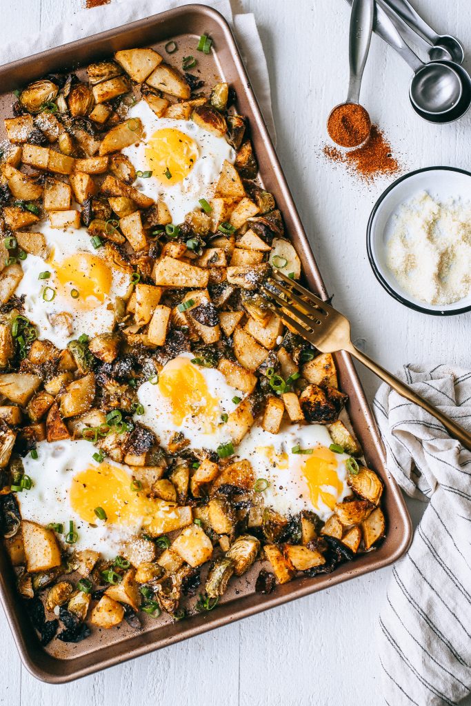 potatoes brussels sprouts and eggs in a baking tray with gold fork