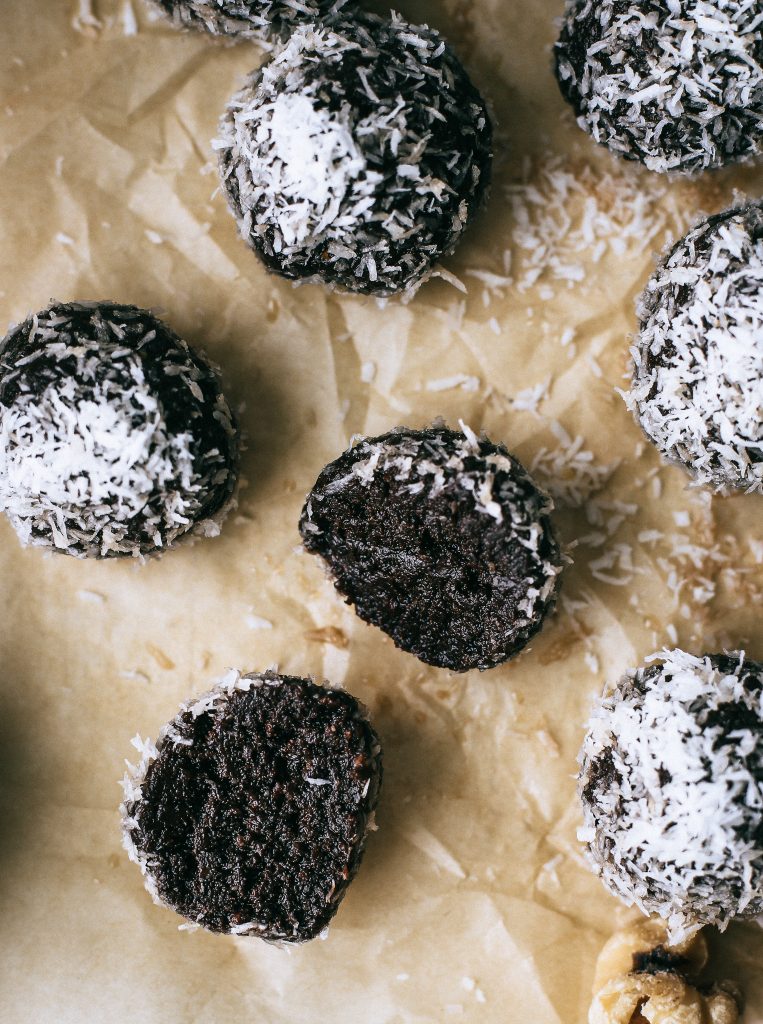 chocolate energy balls rolled in coconut on parchment paper