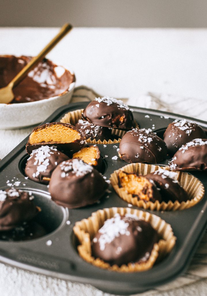 peanut butter chocolate truffles with flaky sea salt in a cupcake tin with a bowl of melted chocolate 