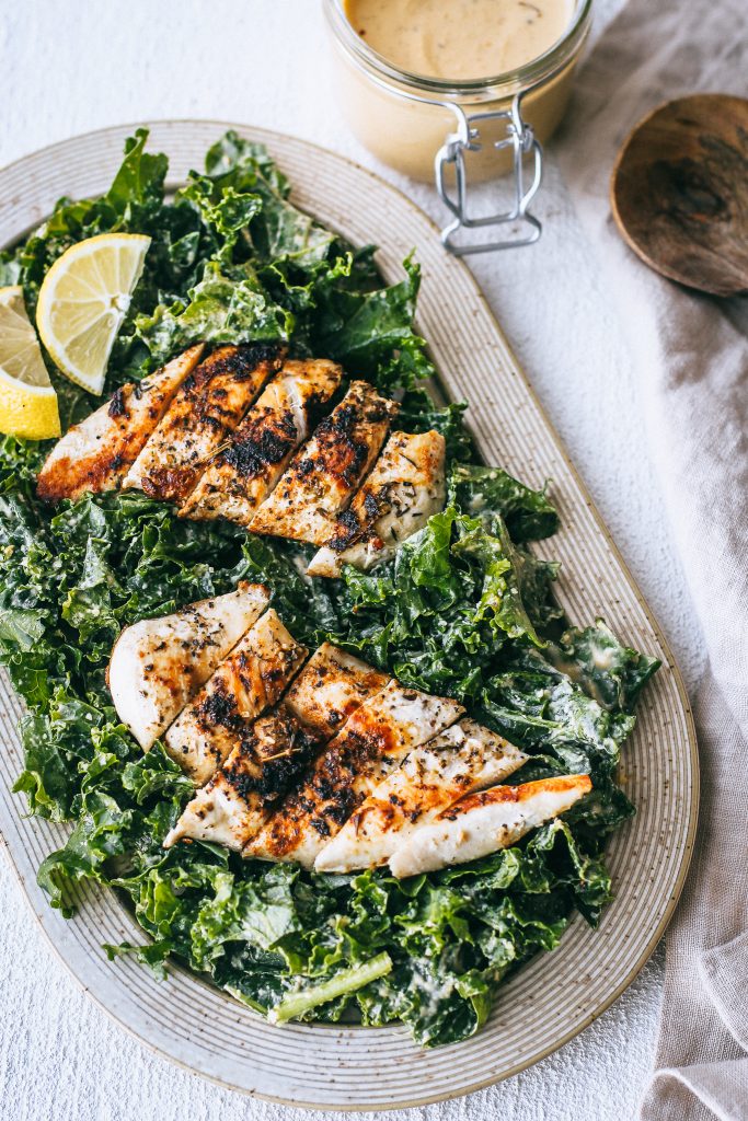 kale salad with sliced chicken breasts on platter