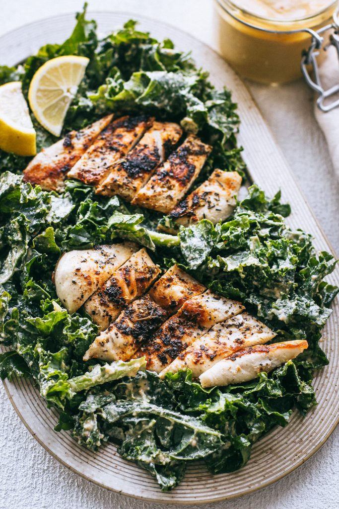 kale salad with sliced chicken breasts on platter