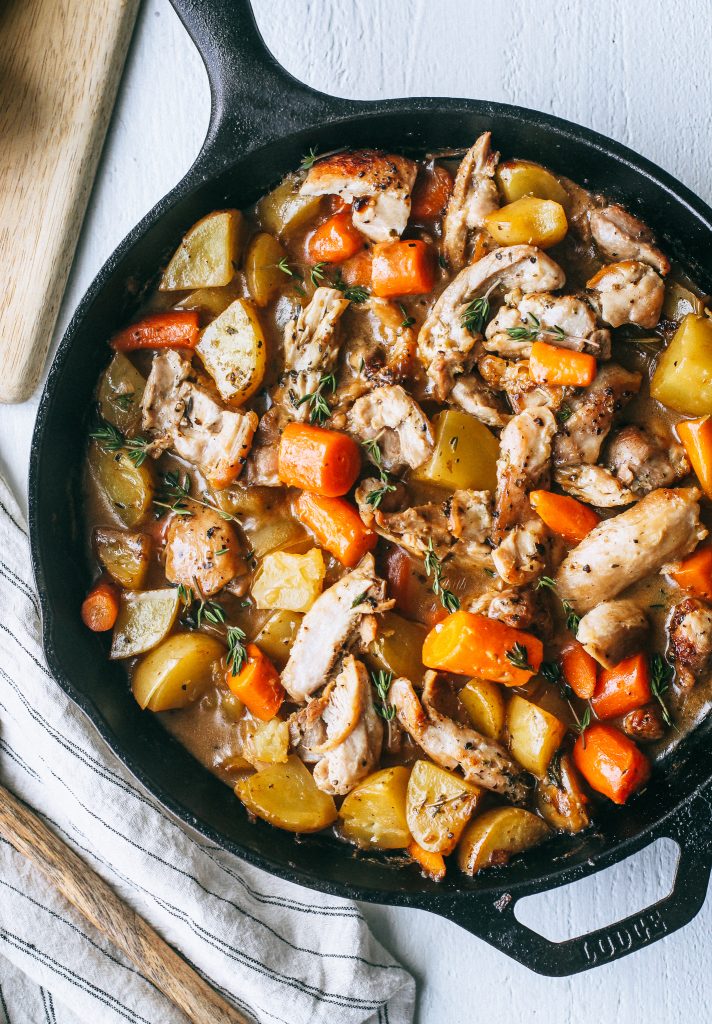 chicken, potatoes, and carrots in a creamy white wine sauce in black skillet
