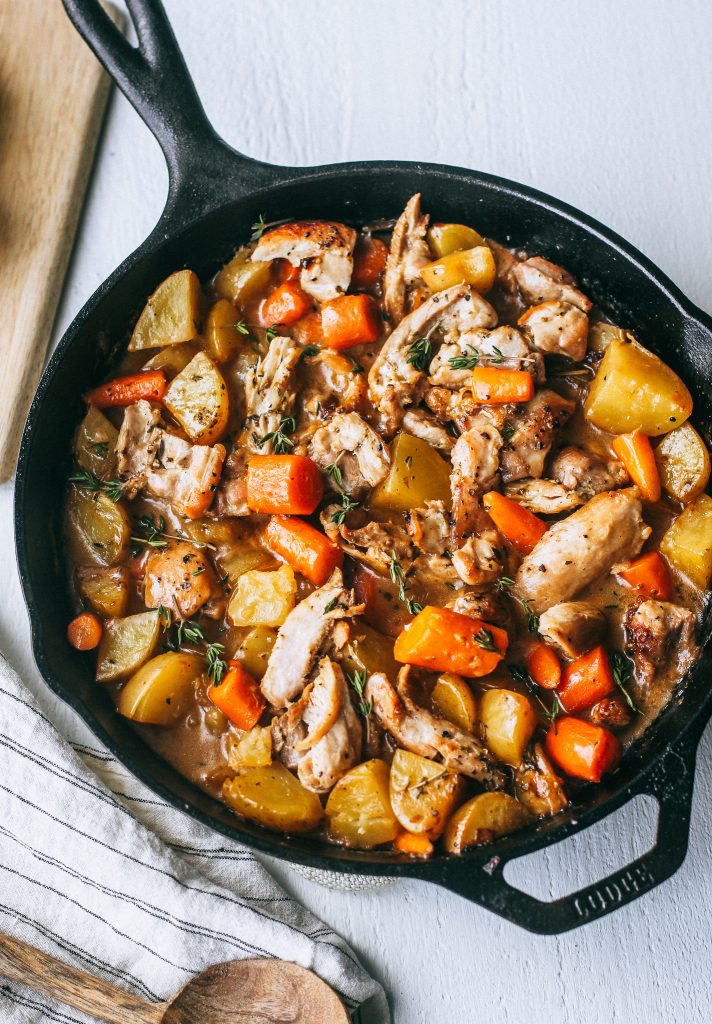 chicken, potatoes, and carrots in a creamy white wine sauce in black skillet