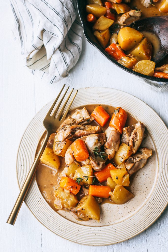 chicken, potatoes, and carrots in a creamy white wine sauce on a plate with gold fork