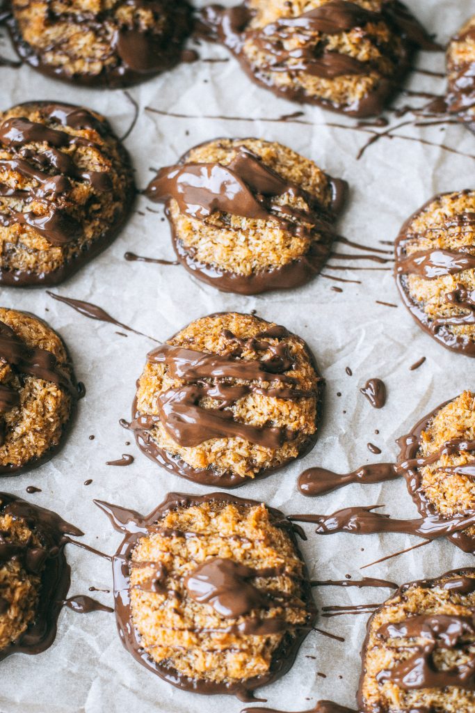 samoa cookies topped with melted chocolate on parchment paper