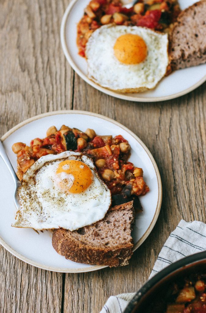 eggs with zucchini and eggplant and chickpea sauce on plates with toast
