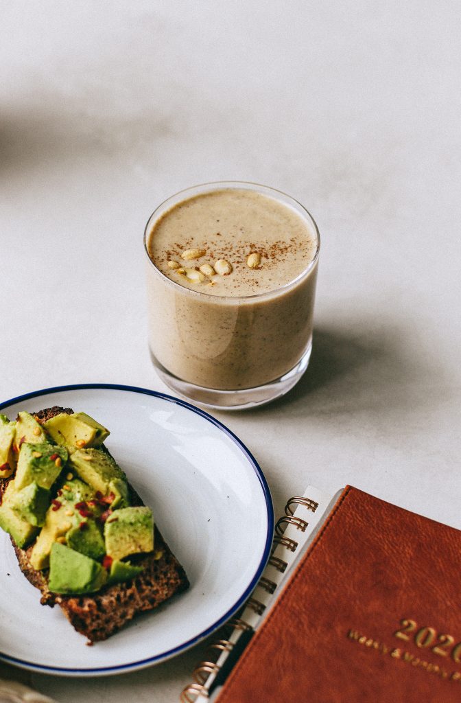 salted caramel smoothie topped with peanuts, avocado toast on plate, daily planner