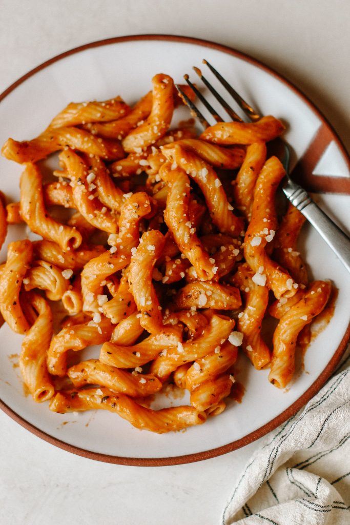 creamy vegan tomato pasta on white plate with fork