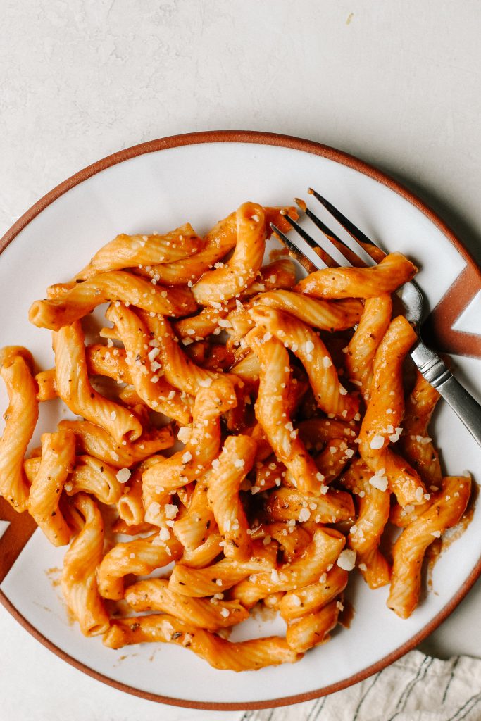 creamy vegan tomato pasta on white plate with fork