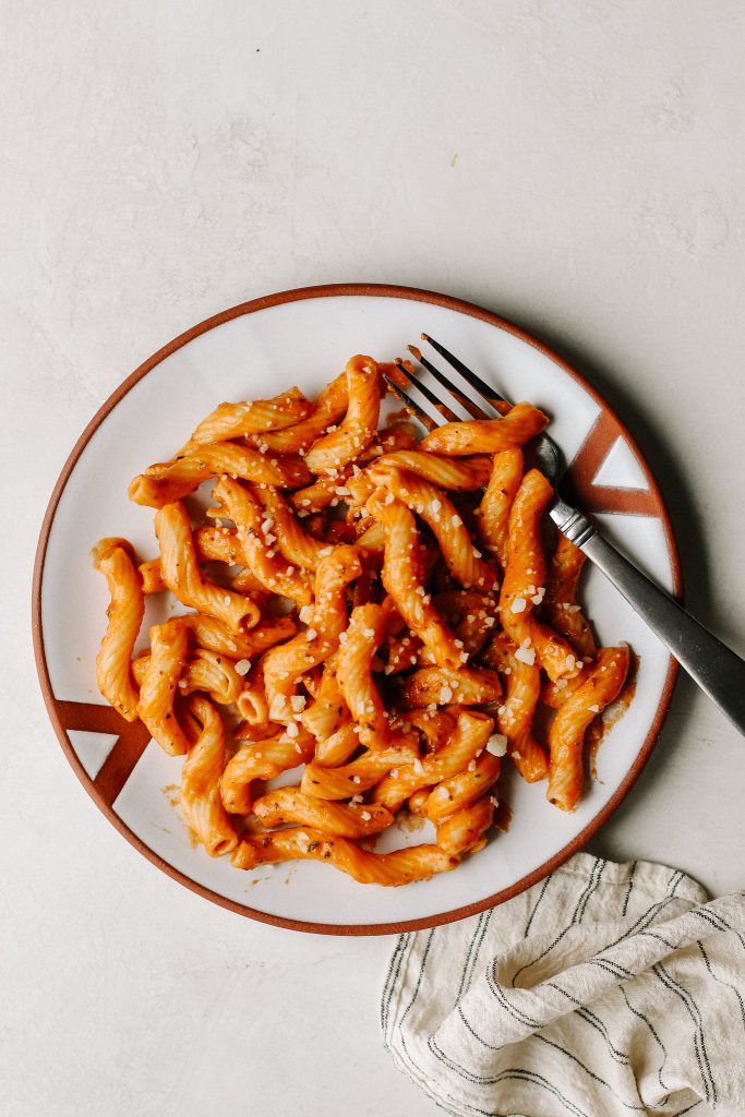 creamy vegan tomato pasta on white plate with fork