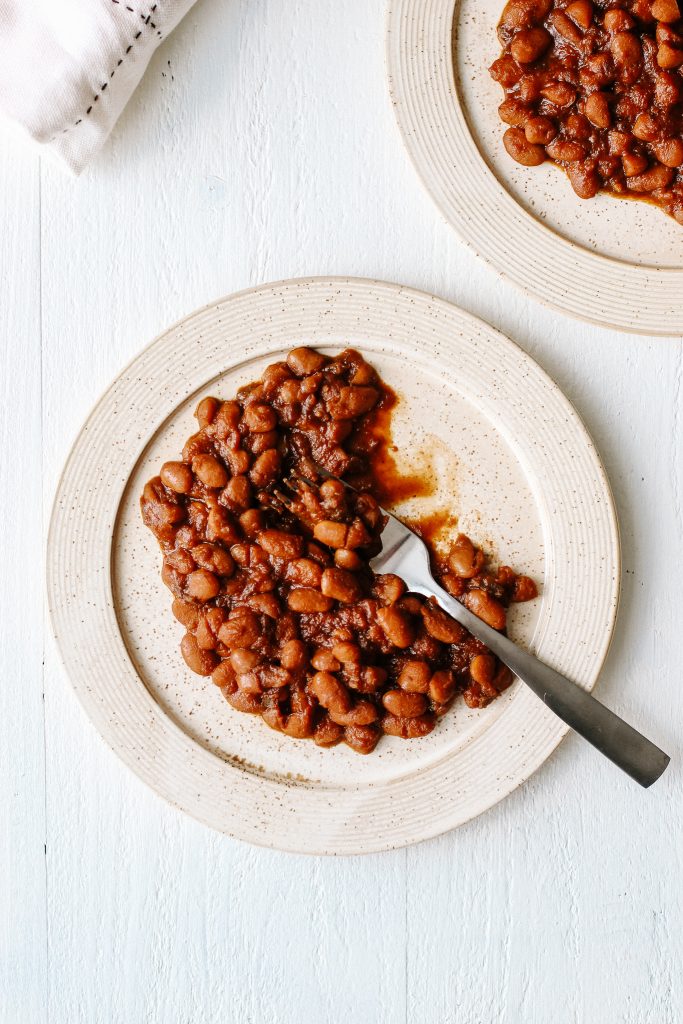 Vegan bbq baked beans on plate with fork and pot of beans