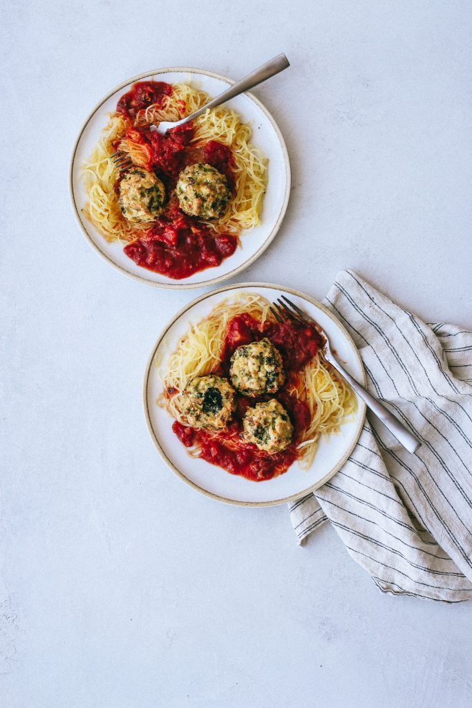 broccoli chicken meatballs with spaghetti squash and marinara on plates with dish towel