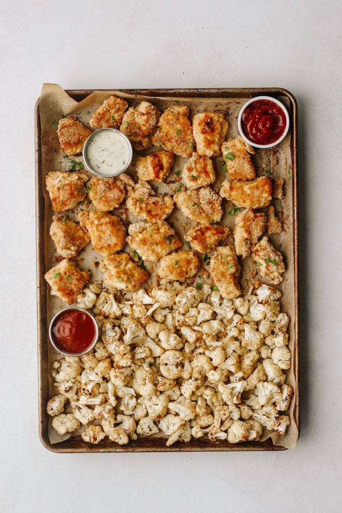 paleo chicken nuggets and cauliflower on a baking sheet with dips