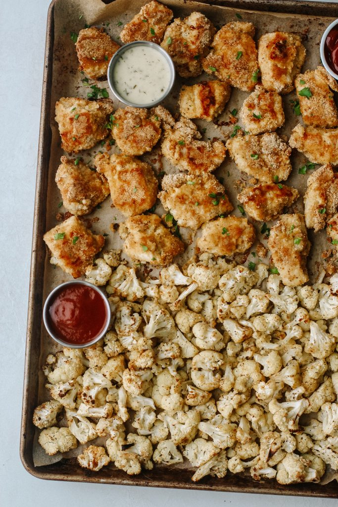 paleo chicken nuggets and cauliflower on a baking sheet with dips