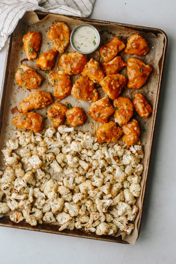 buffalo chicken and cauliflower on a sheet pan with a bowl of ranch