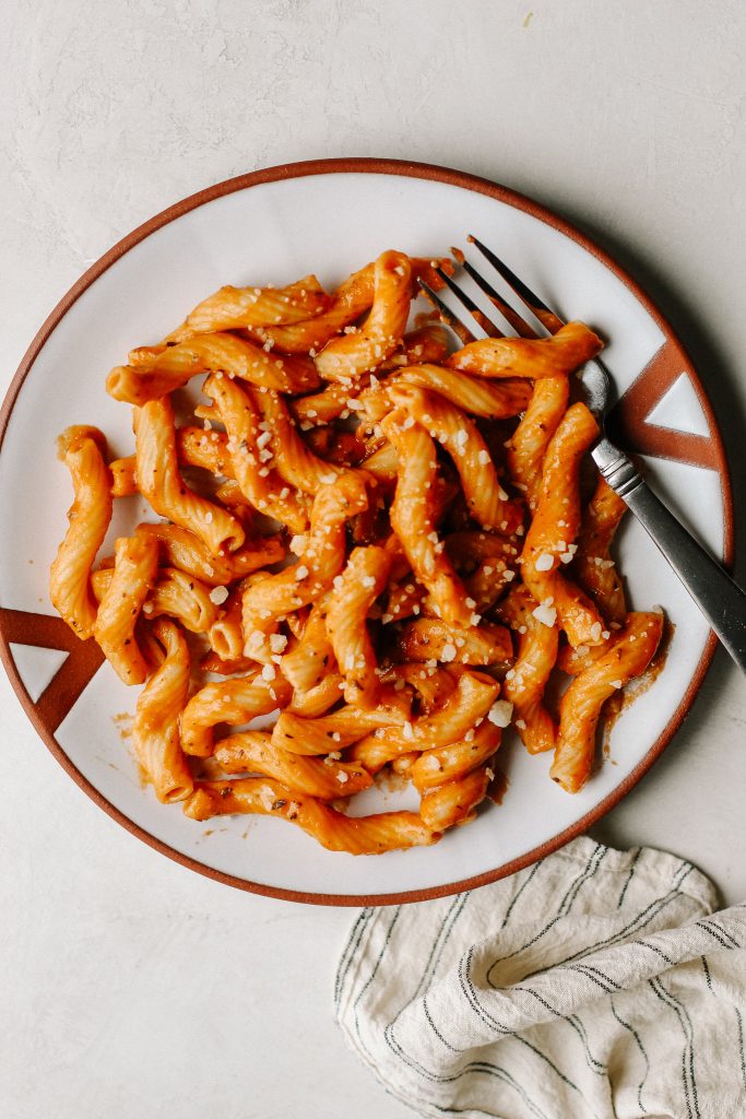 creamy vegan tomato pasta on white plate with fork