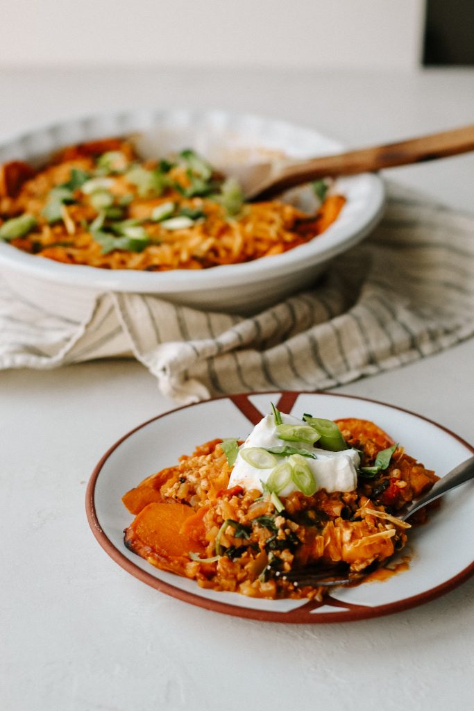 enchilada casserole on plate with sour cream and green onion