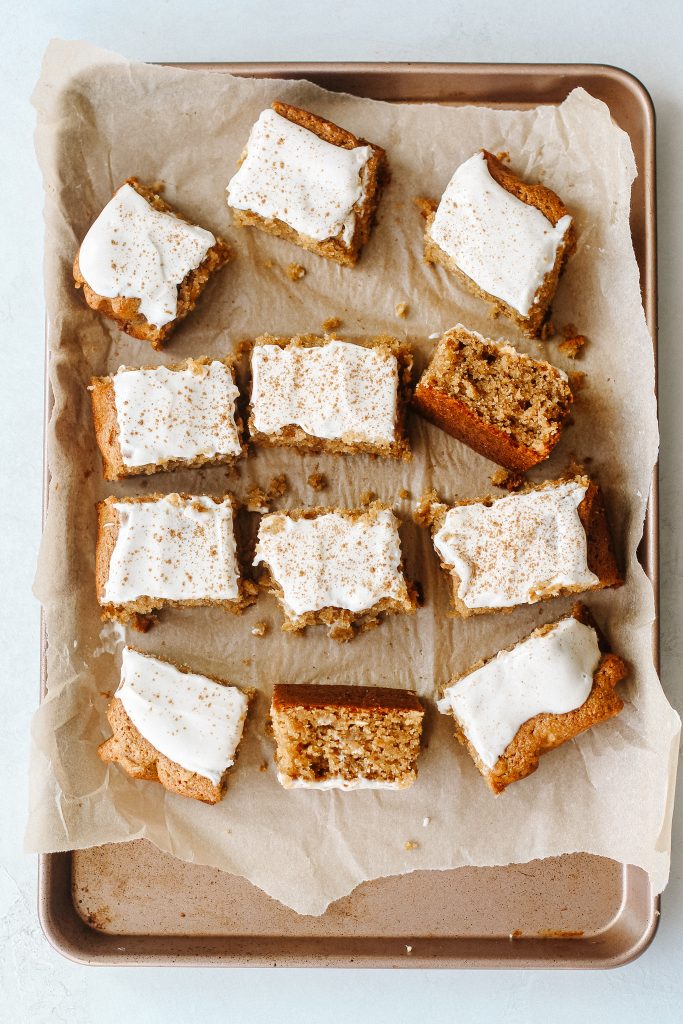 slices of maple cake with frosting on parchment paper and baking sheet