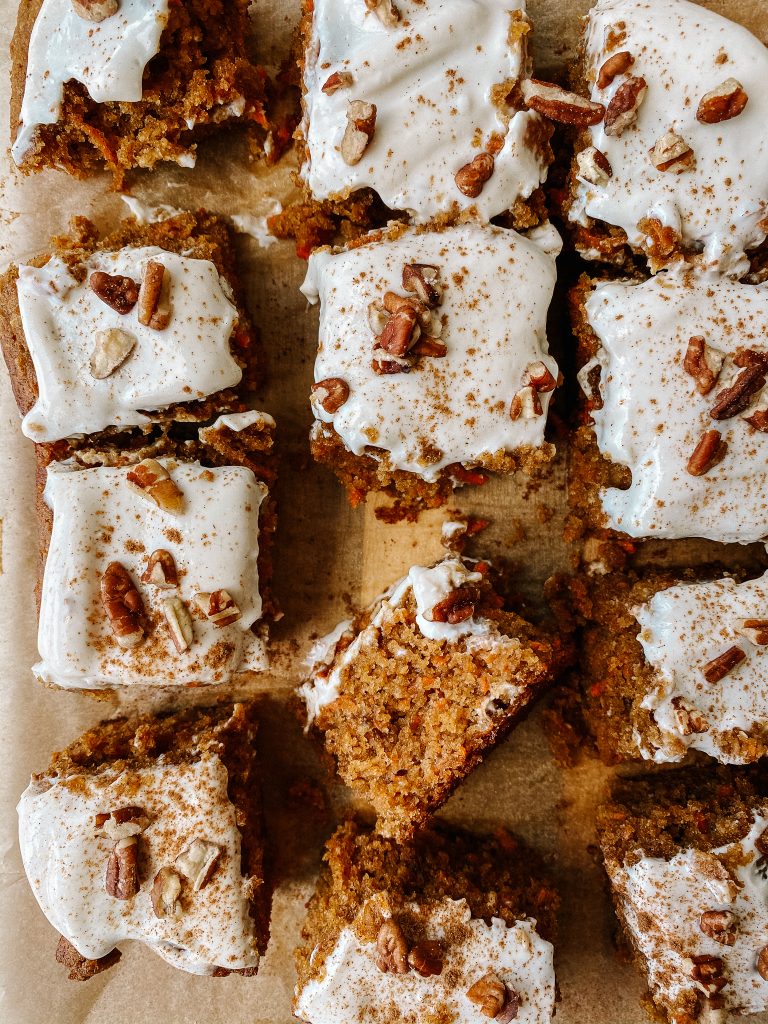 carrot cake square slices with cream cheese frosting and chopped pecans