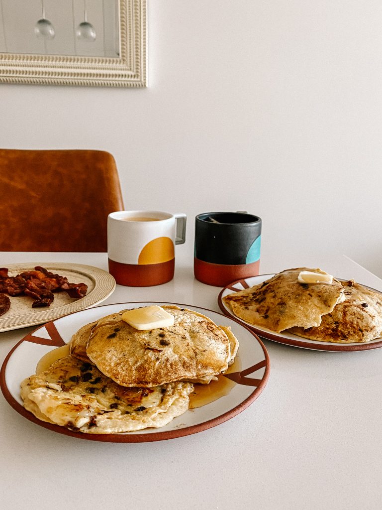 pancakes and bacon on plates with coffee mugs