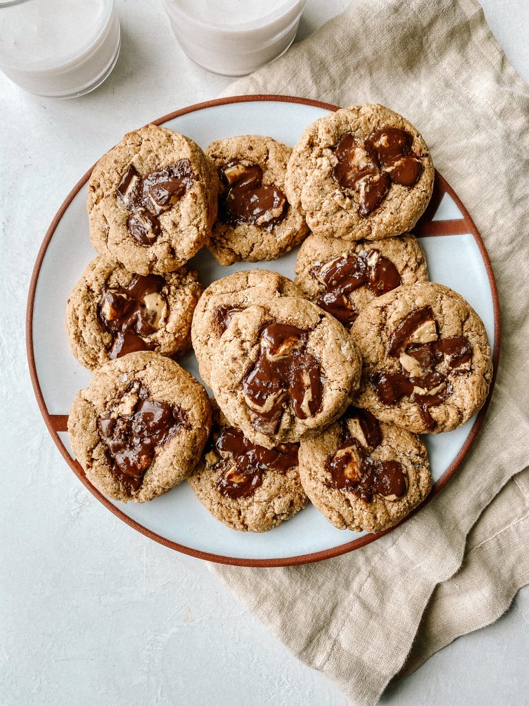 peanut butter cup cookies on a plate with 2 cups of milk