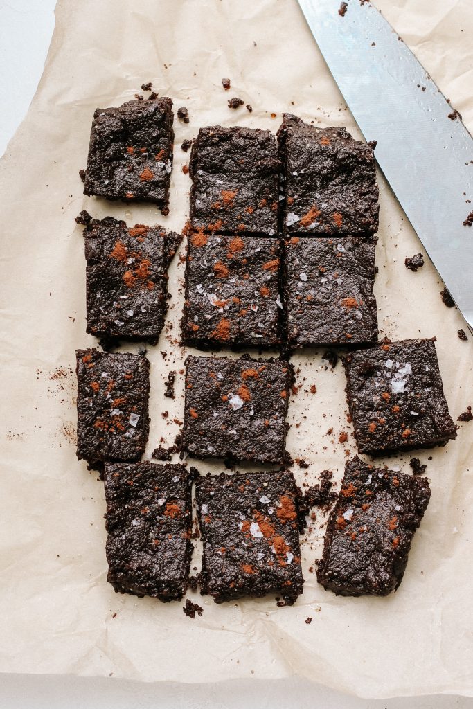 raw peppermint brownie energy squares sliced on parchment paper with a knife