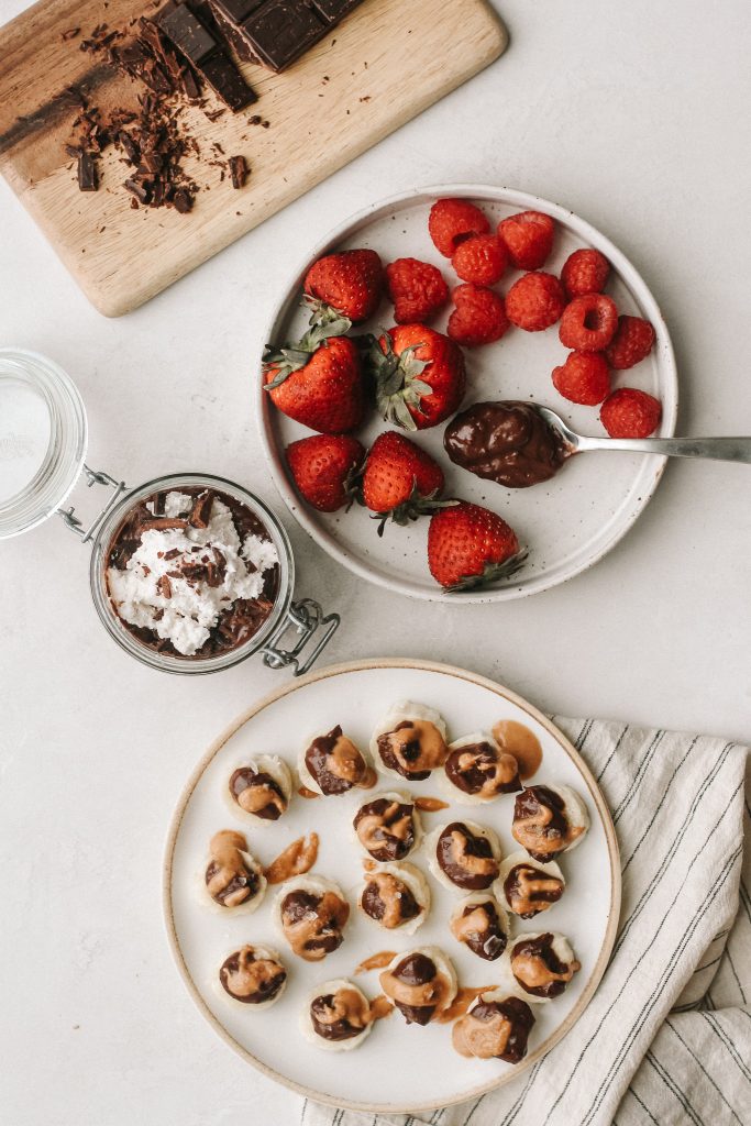 plate of berries with chocolate pudding on spoon, chocolate pudding in jar, banana slices with chocolate and peanut butter