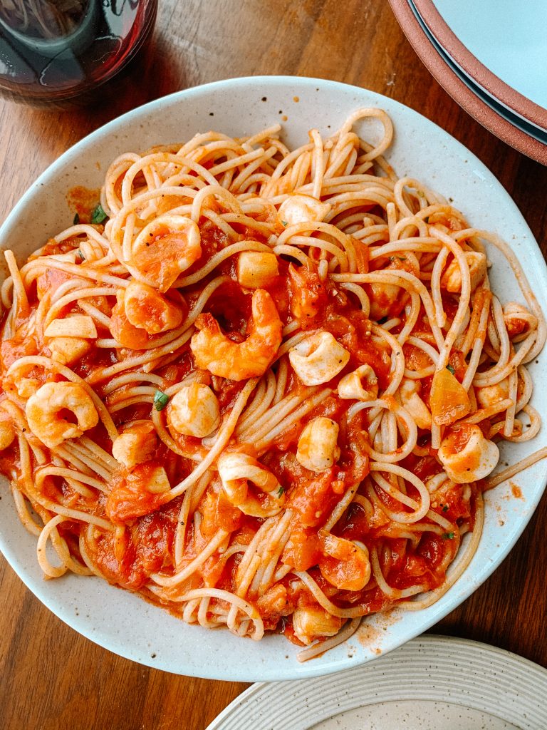 seafood pasta in a bowl with glass of wine