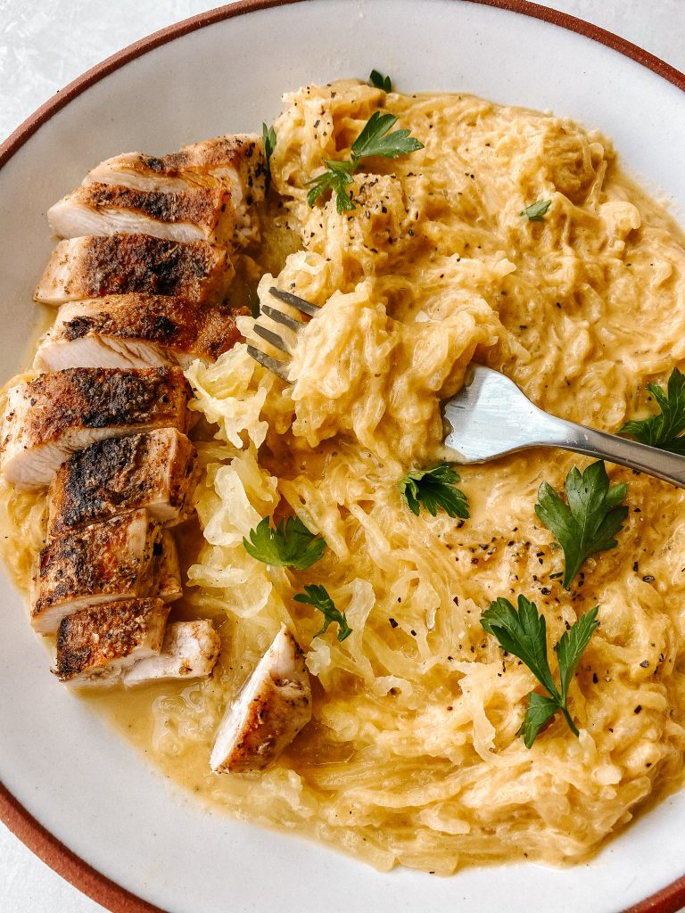 spaghetti squash with butternut mac and cheese sauce with sliced chicken breast and a fork