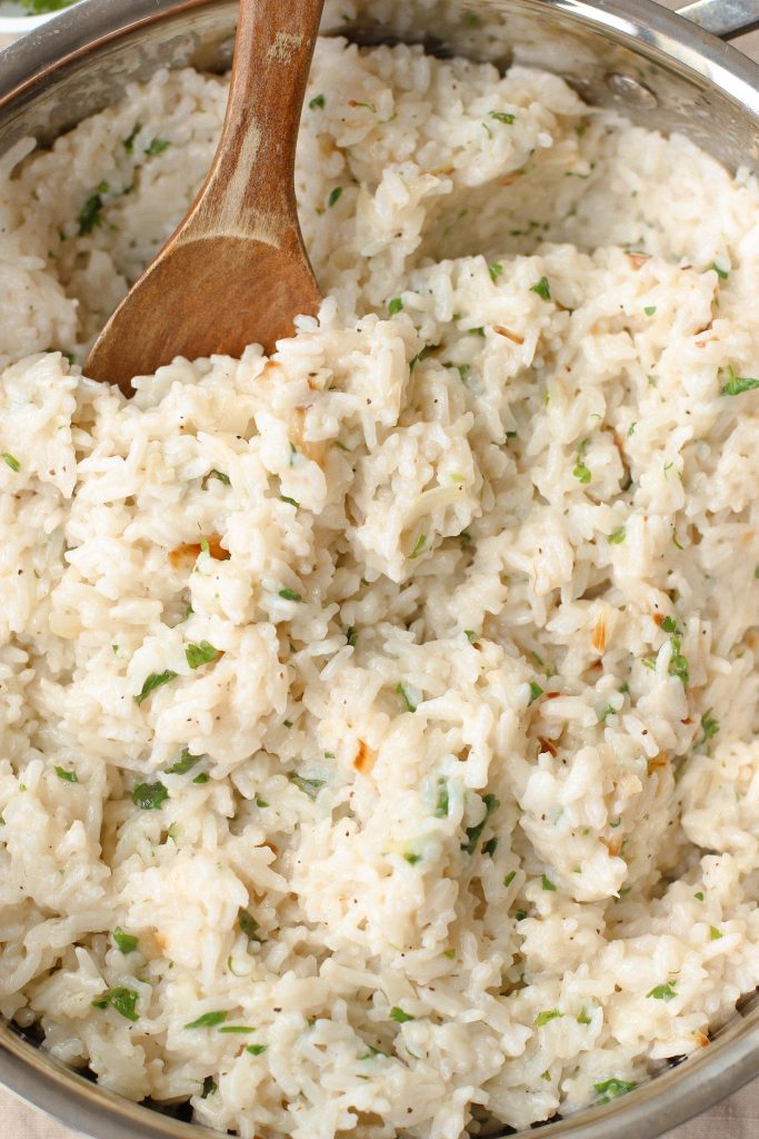 Creamy coconut lime rice in a pan with wooden spoon
