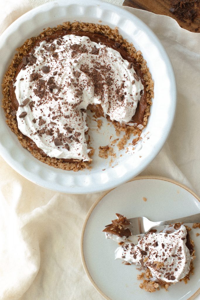 chocolate mousse pie with cool whip topping in a pie dish with a slice on a plate