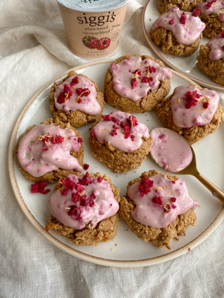 cookies with raspberry yogurt frosting on plates with cup of yogurt