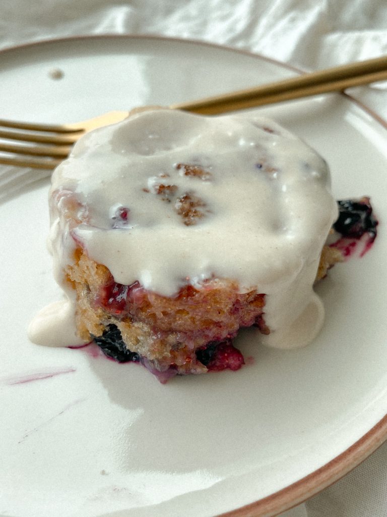 blueberry cinnamon roll on a plate with a gold fork 