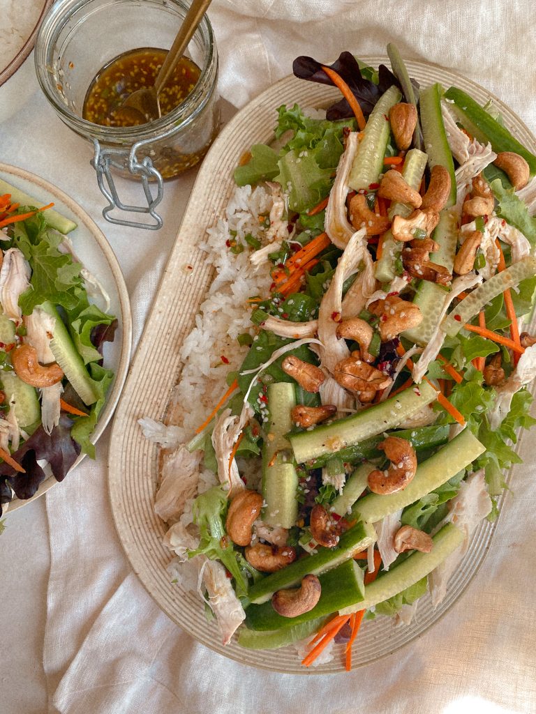 cashew chicken salad and rice on a platter with jar of salad dressing