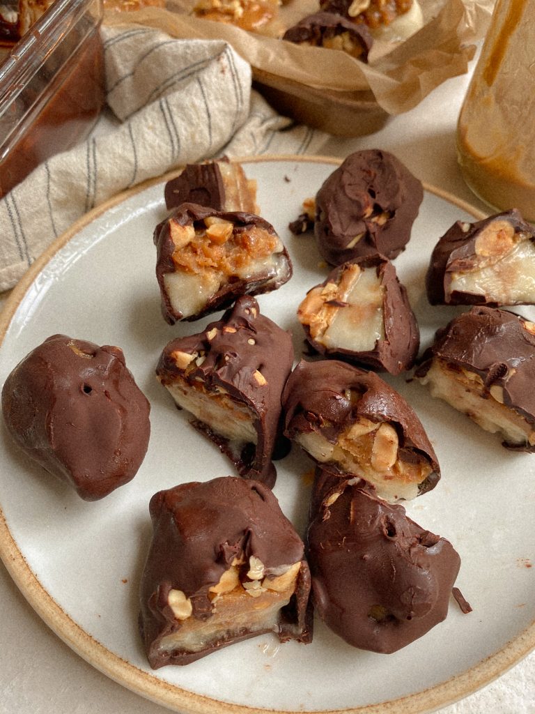 banana snickers bites on a plate with caramel and chocolate in the background