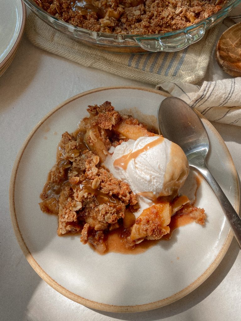 apple crisp with ice cream and caramel on a plate with a spoon