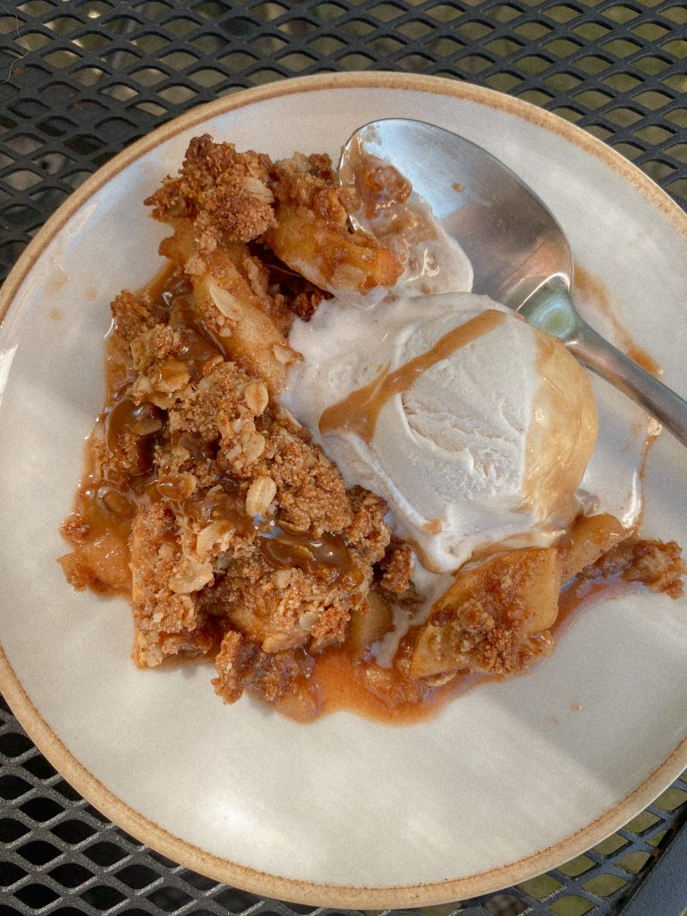 apple crisp with ice cream and caramel on a plate with a spoon
