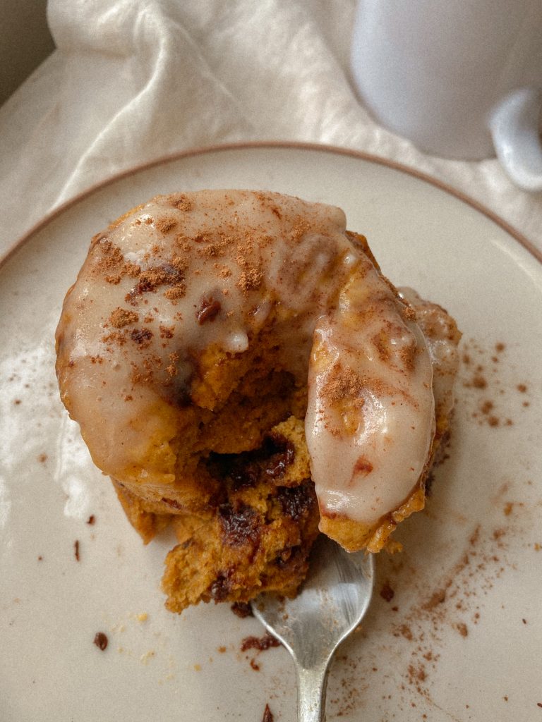 pumpkin mug cake with cream cheese glaze and cinnamon on a plate with a spoon